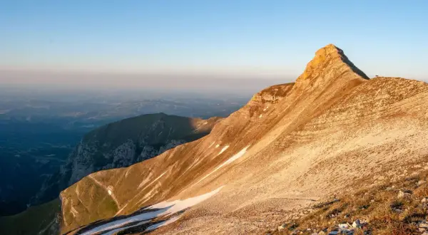 Alba dorata sulla Sibilla Appenninica, con valli nebbiose e un rifugio solitario in vetta.