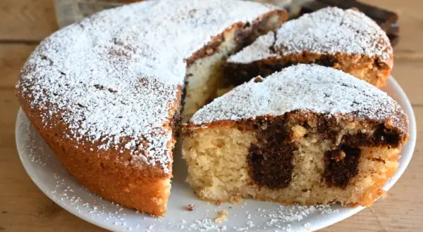 Torta variegata con zucchero a velo, un classico che conquista con il suo contrasto di sapori e la sua morbidezza.
