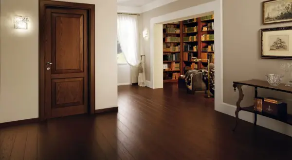 Un elegante corridoio con un battiscopa diverso dalle porte in legno scuro, che conduce a una biblioteca ricca di libri.