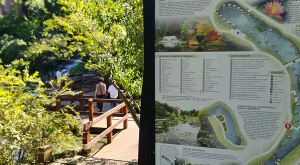 Blick auf den botanischen Garten Breslau mit einer Karte der Wasserpflanzen und einem Weg durch üppiges Grün.