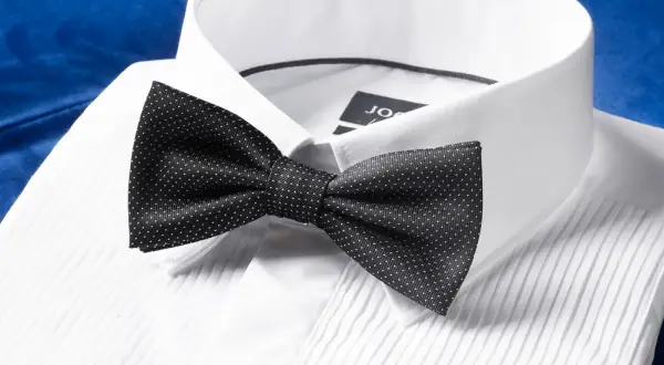 Czarna mucha w kropki na białej koszuli. Dowiedz się, jak założyć muchę, by wyglądać elegancko.