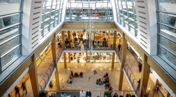 Blick in ein helles Einkaufszentrum in Bergisch Gladbach mit vielen Besuchern, Geschäften und Sitzbereichen.