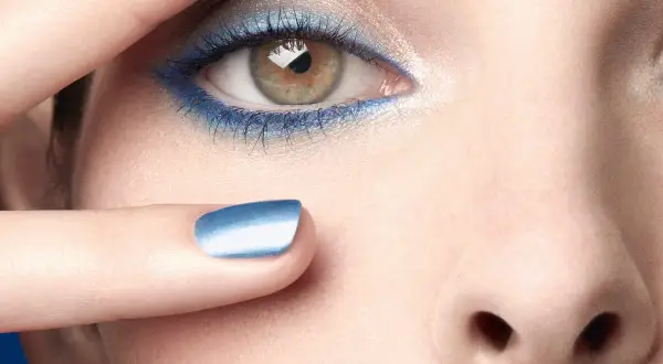 Occhi con ombretto blu elettrico e unghie abbinate, un tocco di **chanel cipria** per un look audace.
