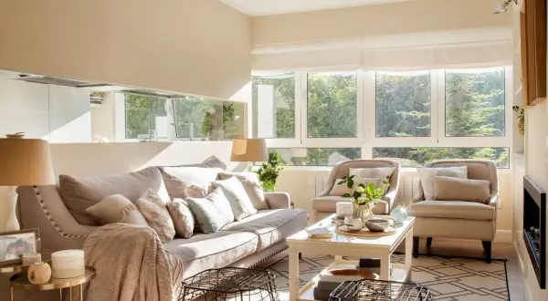 Salón luminoso con sofá y sillones en tonos neutros. La paleta de colores para pintar salones es cálida y acogedora, inspirada en la luz natural.