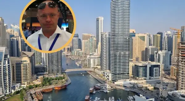 Mężczyzna w okularach na tle Dubaju. Dowiedz się, ile kosztują mieszkania w Dubaju i jakie są ceny nieruchomości w tym mieście.