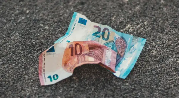 Uszkodzone banknoty 10 i 20 euro leżą na szarej powierzchni. Dowiedz się, gdzie wymienić uszkodzony banknot euro.