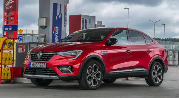 Czerwony Renault Arkana na stacji paliw. Wiele osób szuka **Renault Arkana opinie** przed zakupem.