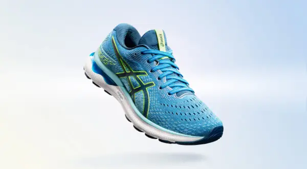 Scarpa da running Asics Gel Nimbus 24 uomo blu con dettagli gialli, in volo su sfondo sfumato.