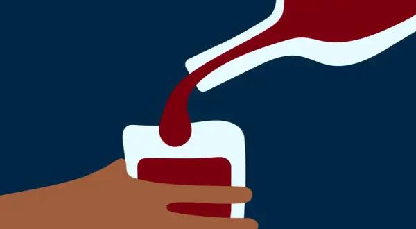 En hand håller ett glas medan mörkt vin hälls upp. En bild som kan symbolisera alkoholist beteende.