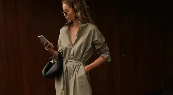 Kvinna i en snygg skjortklänning med bälte, solglasögon och handväska. En perfekt look för vårmode 2026 dam.