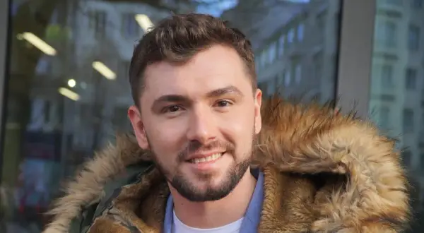 Uśmiechnięty Kamil Bednarek w futrzanej kurtce. Może właśnie wraca do swojej żony po koncercie.
