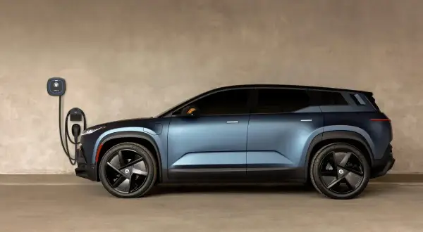 Niebieski Fisker SUV podłączony do ładowarki ściennej. Futurystyczny design i nowoczesna technologia.