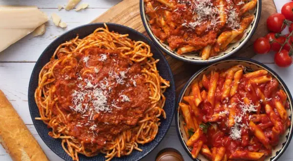Pyszna kolacja bez mięsa: spaghetti i penne w sosie pomidorowym, posypane parmezanem. Idealna dla wegetarian.