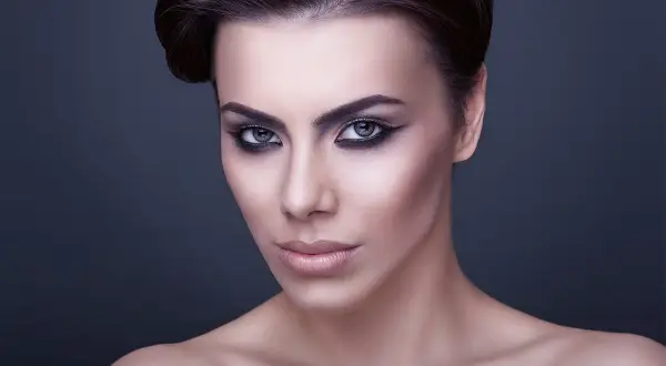 Volto di donna con trucco drammatico, labbra carnose e occhi all'ingiù che catturano lo sguardo.
