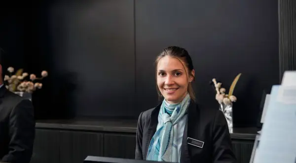 Lächelnde Hotelfachfrau mit Schal, bereit für ihre Weiterbildung.