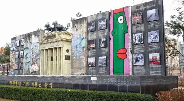 Fragment muru berlińskiego z graffiti i zdjęciami upamiętniającymi historię podzielonych Niemiec.