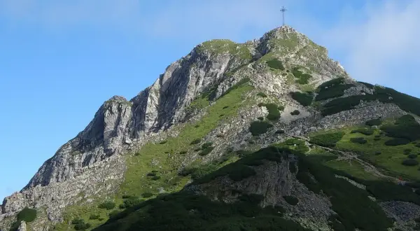 Szczyt Giewontu z krzyżem, symbol Tatr. Widok na skaliste zbocza i zielone hale, które góry są w Zakopanem.