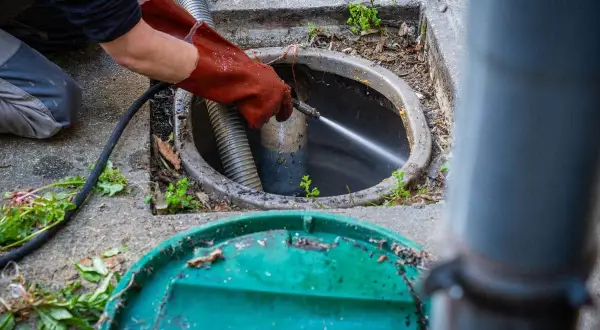 Un professionnel utilise un jet d'eau puissant pour le nettoyage du tuyau d'évacuation, délogeant les obstructions.