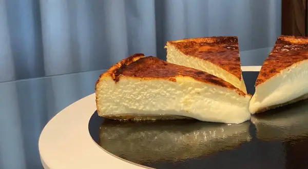 Trois parts de cheesecake basque, avec leur croûte caramélisée et leur cœur crémeux, prêtes à être dégustées.