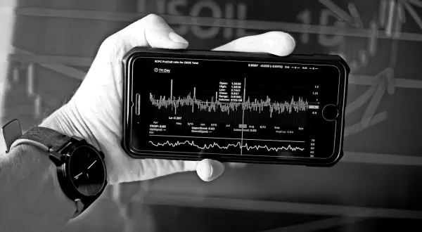 Dłoń trzyma smartfon z wykresem finansowym, analizującym strategię DCA. Widoczne dane rynkowe i wskaźniki.