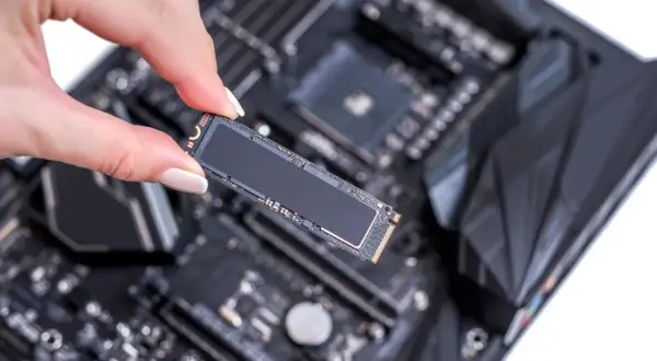 Eine Hand hält eine M.2 SSD, bereit für den Einbau in den entsprechenden ssd steckplatz mainboard.