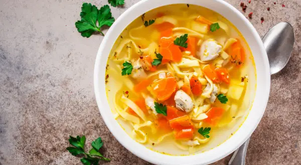 Aromaticzny rosół z indyka z makaronem i marchewką, udekorowany natką pietruszki. Idealny na chłodne dni.