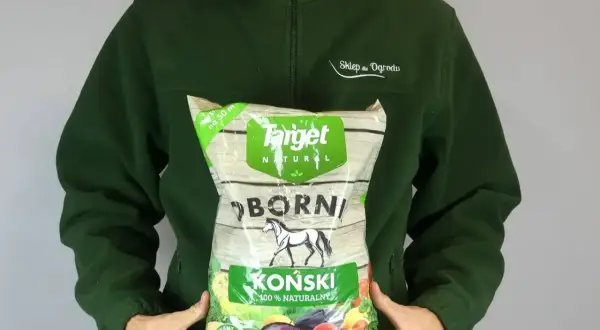 Osoba trzyma worek z napisem "Obornik Koński 100% Naturalny". Granulowany nawóz dla roślin.