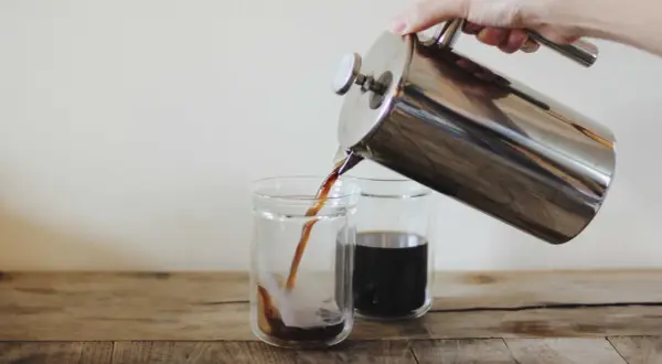 Versando caffè americano da una french press in due bicchieri. Le dosi caffè americano sono perfette per iniziare la giornata.
