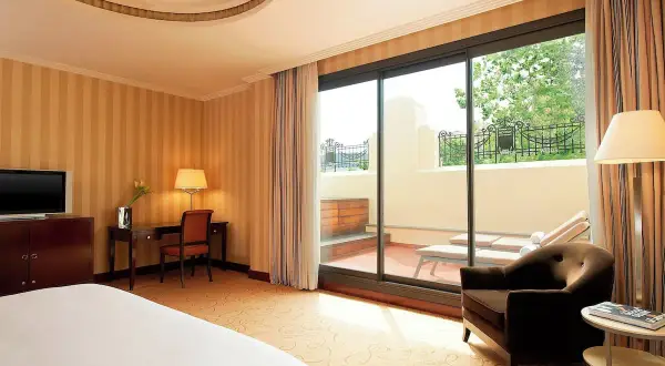 Habitación de lujo con terraza privada y tumbonas, ideal para relajarse tras un día en el spa Westin Valencia.