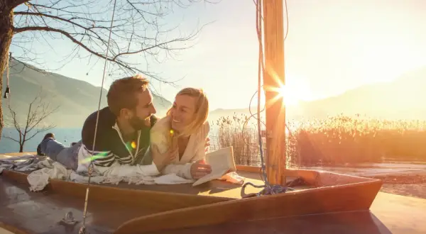 Glückliches Paar auf einem Boot bei Sonnenuntergang. Ihre christliche Partnersuche Erfahrungen haben sie hierher geführt.
