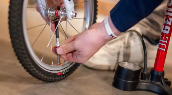 Hand sluit fietspomp aan op ventiel. Zo pomp je een fietsband op voor een soepele rit.