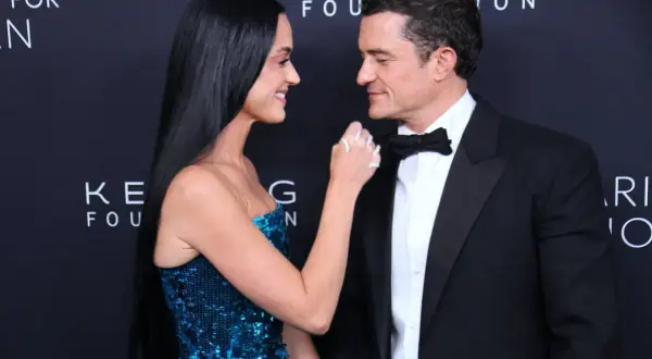 Katy Perry i Orlando Bloom patrzą na siebie z czułością. Ona w błyszczącej sukni, on w eleganckim smokingu.