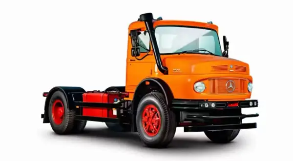 Un gros camion américain orange vif, prêt pour l'aventure, avec un échappement sur le côté.