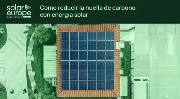 Vista aérea de un tejado con un gran conjunto de placas solares. El texto indica "Cómo reducir la huella de carbono con energía solar".