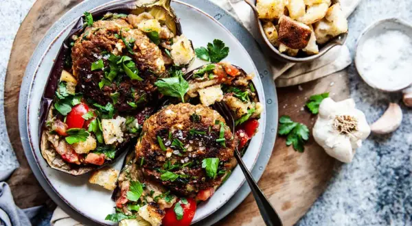 Ugnsbakad aubergine fylld med köttfärs, tomater och krutonger, toppad med färsk persilja. En härlig aubergine i ugn.