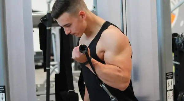 Ein Mann trainiert im Fitnessstudio und baut beeindruckende Muskeln am Oberarm auf.