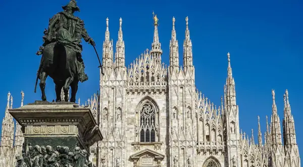Statua equestre davanti al maestoso Duomo di Milano, con le sue guglie che svettano verso il cielo azzurro.
