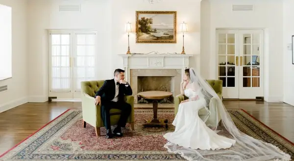Para młoda siedzi naprzeciwko siebie w eleganckim salonie. Zastanawiają się, kto może udzielić im ślubu.