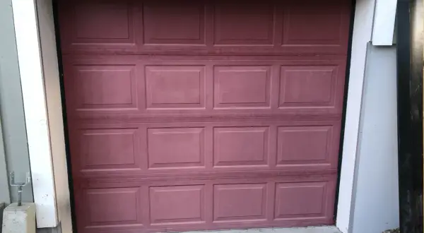 En mörkröd garageport i aluminium, redo att måla om för ett fräschare utseende.