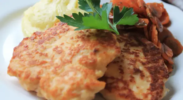 Två gyllene havets wallenbergare serveras med krämigt potatismos och glaserade morötter, toppat med en kvist persilja.