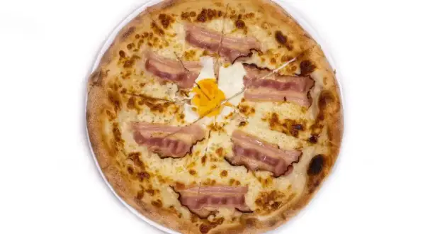 Pizza carbonara z chrupiącym boczkiem i jajkiem na środku. Idealna na szybki obiad.