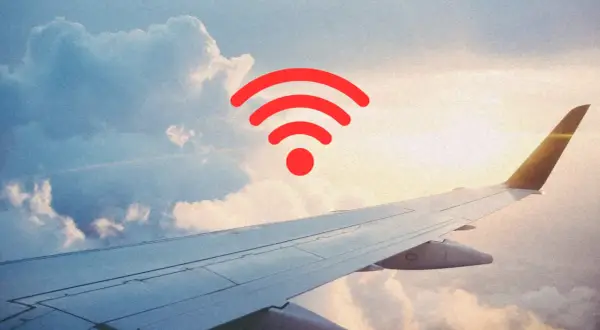 Widok z okna samolotu na chmury i skrzydło. Czerwony symbol Wi-Fi sugeruje, czy w samolocie jest wifi.