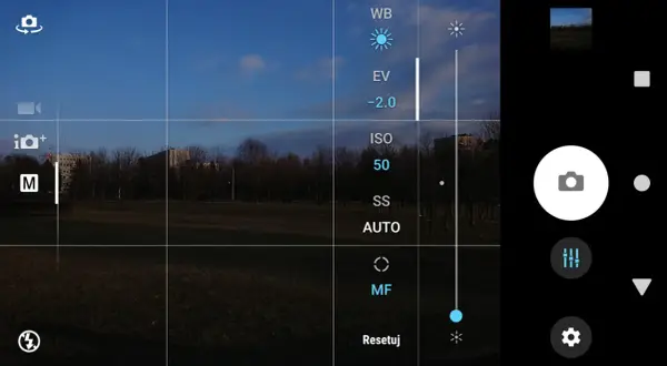 Aparat w telefonie z widokiem na park. Na ekranie opcje: WB, EV, ISO 50, SS AUTO, MF. Jak ustawić długi czas naświetlania w telefonie?