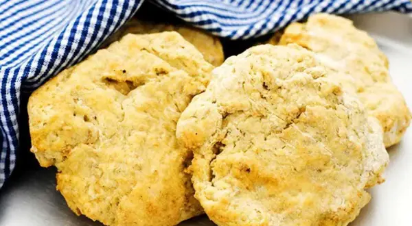 Nyttiga scones, gyllene och fluffiga, vilar under en blåvitrutig handduk. Perfekt för en hälsosam fika.