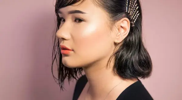 Ein Mädchen mit dunklen, nassen Haaren, die mit Glitzer-Haarnadeln geschmückt sind. So kann man seine **Haare richtig stylen** für einen besonderen Look.
