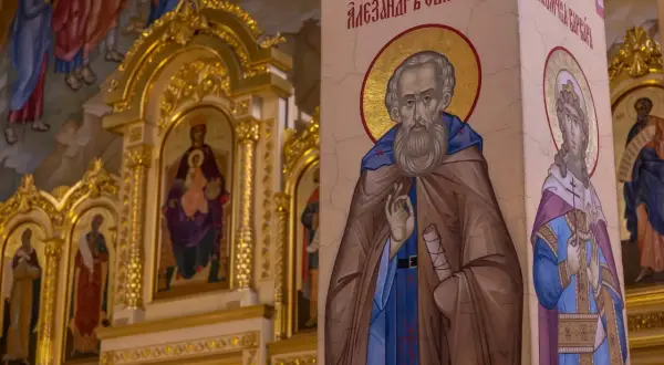 Ikona świętego z brodą i aureolą, obok niej postać kobieca. W tle złota ikona Matki Boskiej z Dzieciątkiem. Motyw sztuki sakralnej.