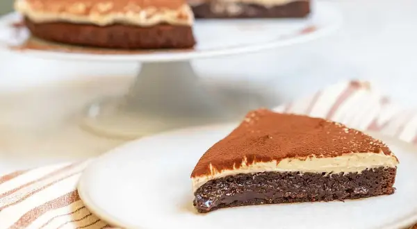 En saftig kladdkaka med en krämig topping, pudrad med kakao. Perfekt för fikat!