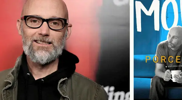 Moby w okularach i z brodą, obok plakat z napisem "Moby Play" i jego podobizną.