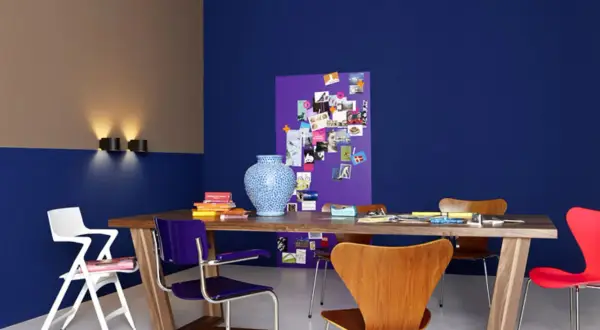 Zweifarbig gestrichene Wand in Blau und Beige mit einem Holztisch, bunten Stühlen und einer Pinnwand. Tolle wand zweifarbig streichen ideen!