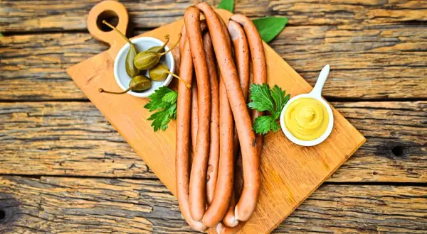 Parówki z szynki na desce z kaparami i musztardą. Idealne na grilla lub jako dodatek do dania.